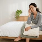 Adult waking up in bed with a headache while holding their forehead, representing common morning headache causes and sleep-related triggers