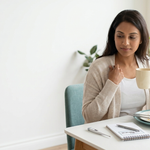 Adult holding a warm mug after a meal while tracking symptoms of feeling cold after eating.